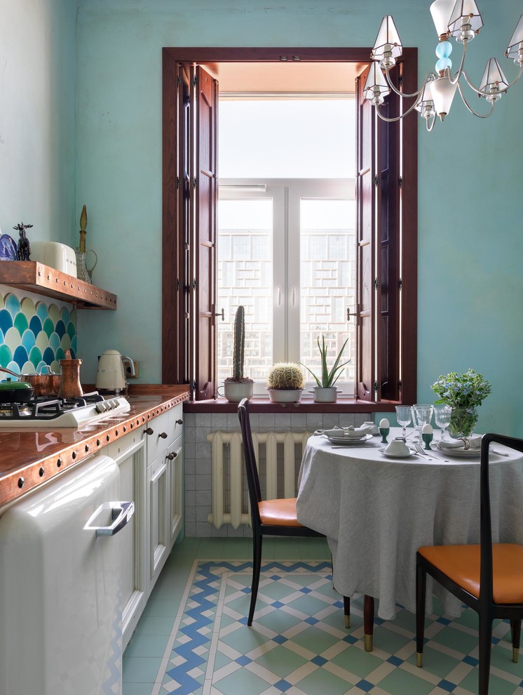 Стильный дизайн: маленькая прямая кухня в стиле ретро с обеденным столом, одинарной мойкой, фасадами с утопленной филенкой, белыми фасадами, столешницей из меди, разноцветным фартуком, фартуком из керамической плитки, белой техникой, полом из керамической плитки, разноцветным полом и оранжевой столешницей для на участке и в саду - последний тренд