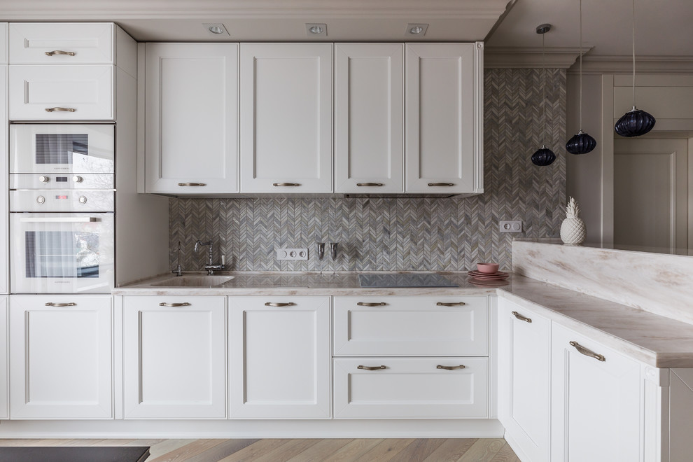 Immagine di una cucina contemporanea con lavello integrato, ante con riquadro incassato, ante bianche, paraspruzzi grigio, elettrodomestici bianchi, pavimento beige e top beige