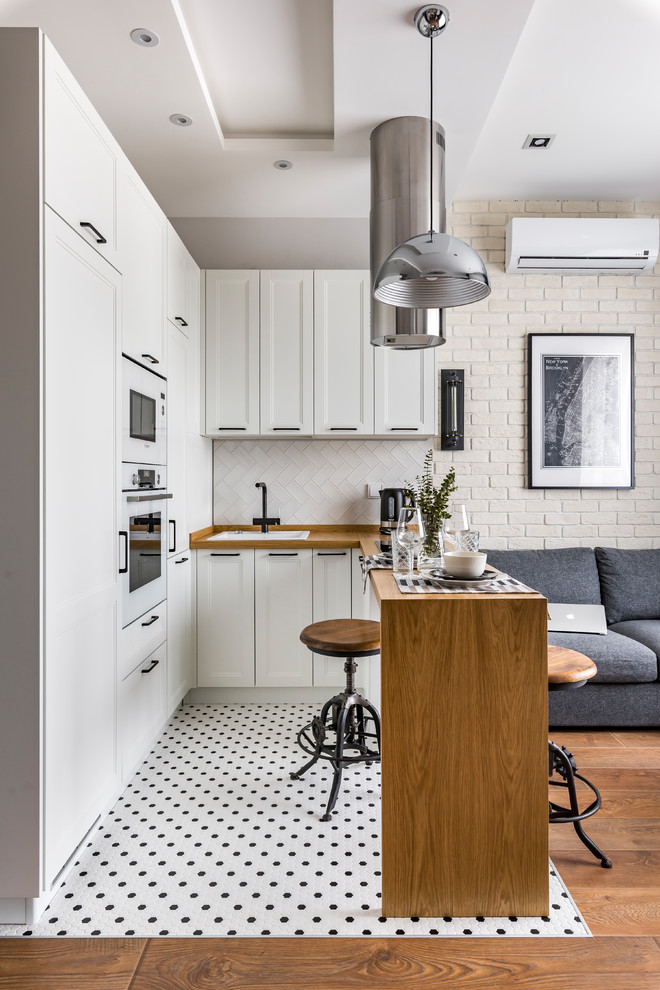 Inspiration for a small contemporary u-shaped multicolored floor open concept kitchen remodel in Moscow with a drop-in sink, recessed-panel cabinets, white cabinets, wood countertops, white backsplash, white appliances, a peninsula and brown countertops