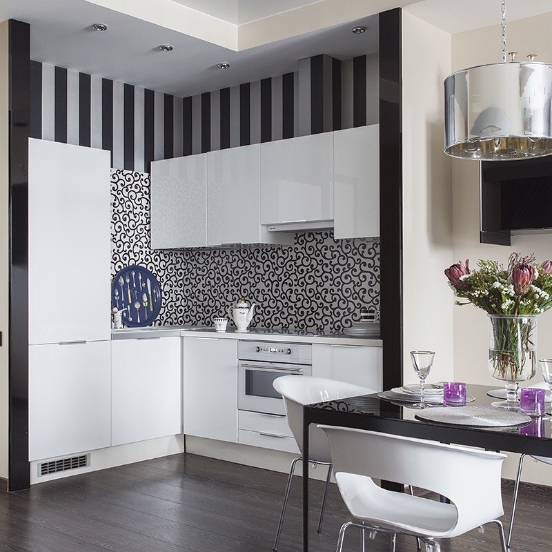 На фото: угловая кухня-гостиная в современном стиле с плоскими фасадами, разноцветным фартуком, белой техникой и черно-белыми фасадами