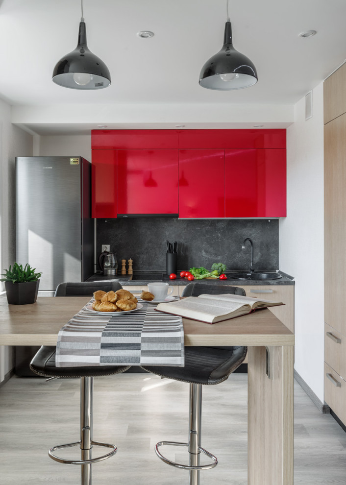 Einzeilige, Kleine Moderne Küche mit Einbauwaschbecken, flächenbündigen Schrankfronten, roten Schränken, Küchenrückwand in Grau, hellem Holzboden, grauem Boden und grauer Arbeitsplatte in Sonstige