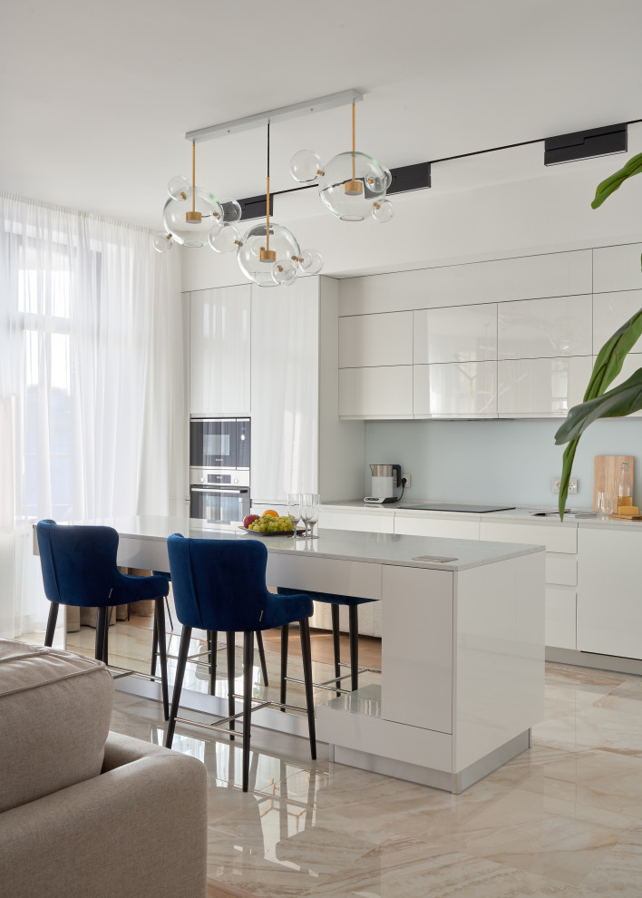 Immagine di una cucina design con ante lisce, ante bianche, pavimento beige, top bianco e elettrodomestici in acciaio inossidabile