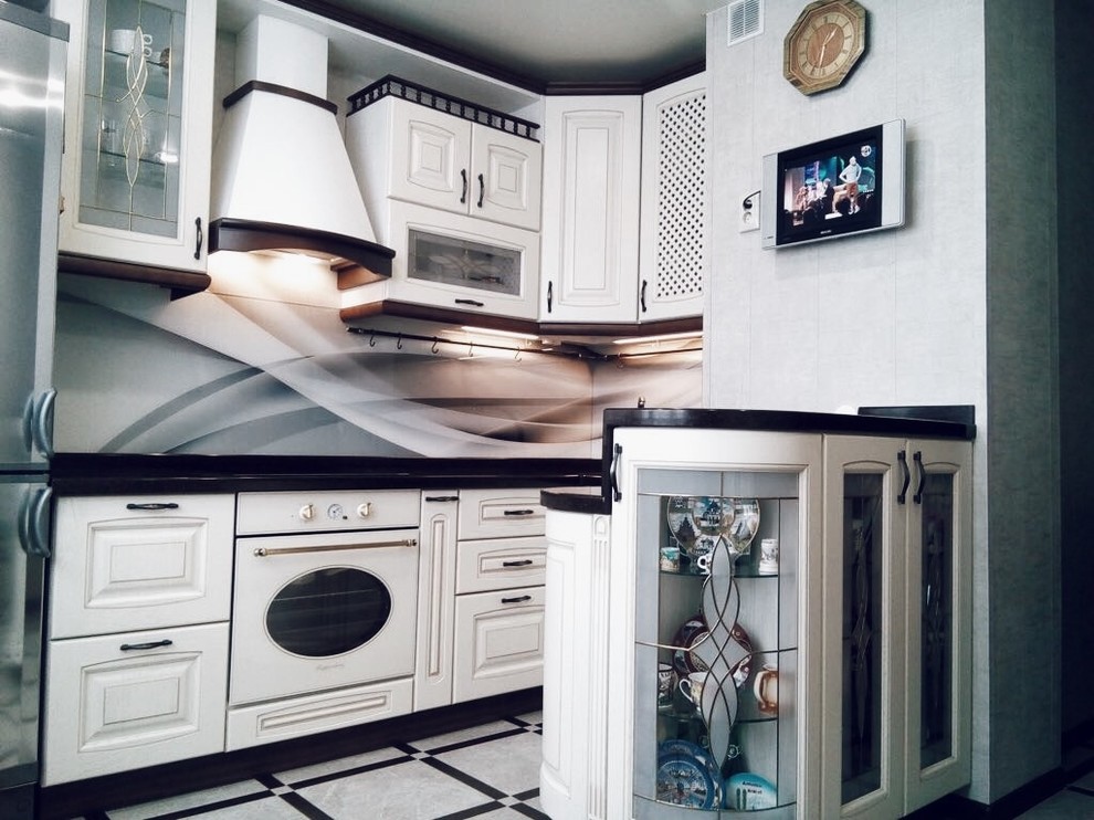 На фото: угловая кухня среднего размера, со стиральной машиной в стиле неоклассика (современная классика) с обеденным столом, стеклянными фасадами и бежевыми фасадами без острова