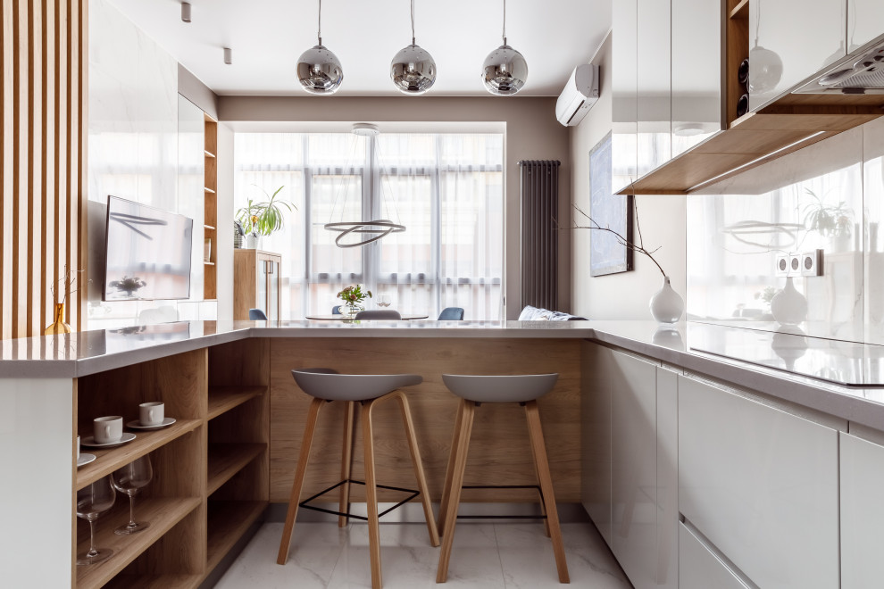 Cette image montre une cuisine ouverte design en U avec un placard à porte plane, des portes de placard grises, une crédence blanche, une péninsule, un sol blanc et un plan de travail gris.