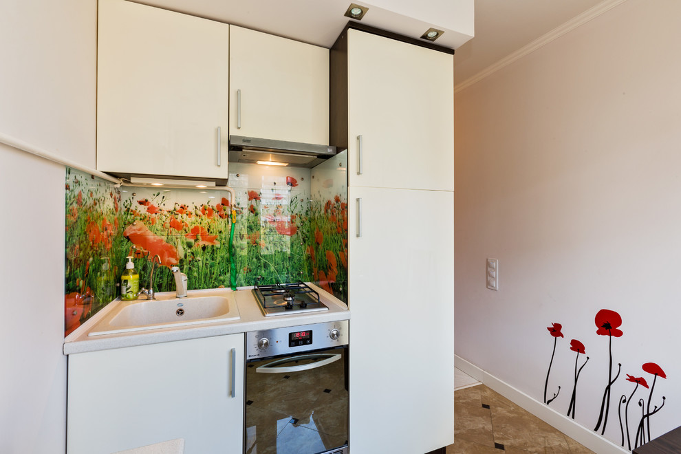 Enclosed kitchen - small contemporary l-shaped ceramic tile enclosed kitchen idea in Moscow with a single-bowl sink, flat-panel cabinets, beige cabinets, laminate countertops, green backsplash, glass tile backsplash, stainless steel appliances and no island