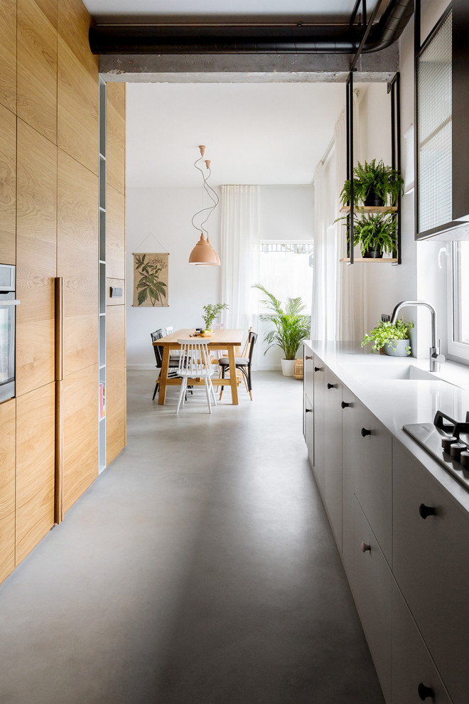 Esempio di una cucina parallela contemporanea con lavello integrato, ante lisce, ante in legno scuro, pavimento in cemento, nessuna isola, pavimento grigio e top bianco