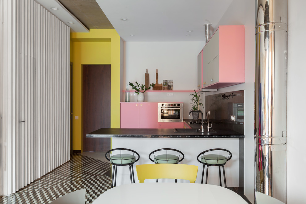 На фото: п-образная кухня-гостиная в стиле фьюжн с накладной мойкой, плоскими фасадами, черным фартуком, техникой из нержавеющей стали, полуостровом и разноцветным полом