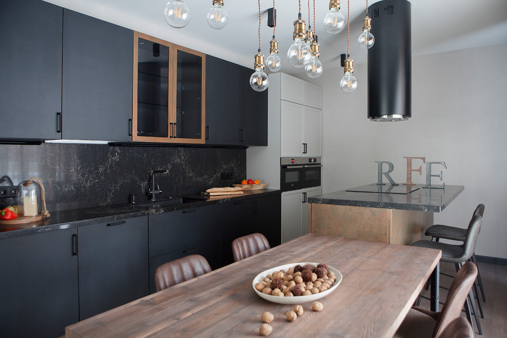 Foto på ett stort funkis svart linjärt kök och matrum, med en undermonterad diskho, svarta skåp, bänkskiva i kvarts, svart stänkskydd, rostfria vitvaror, klinkergolv i porslin, en köksö, brunt golv och släta luckor