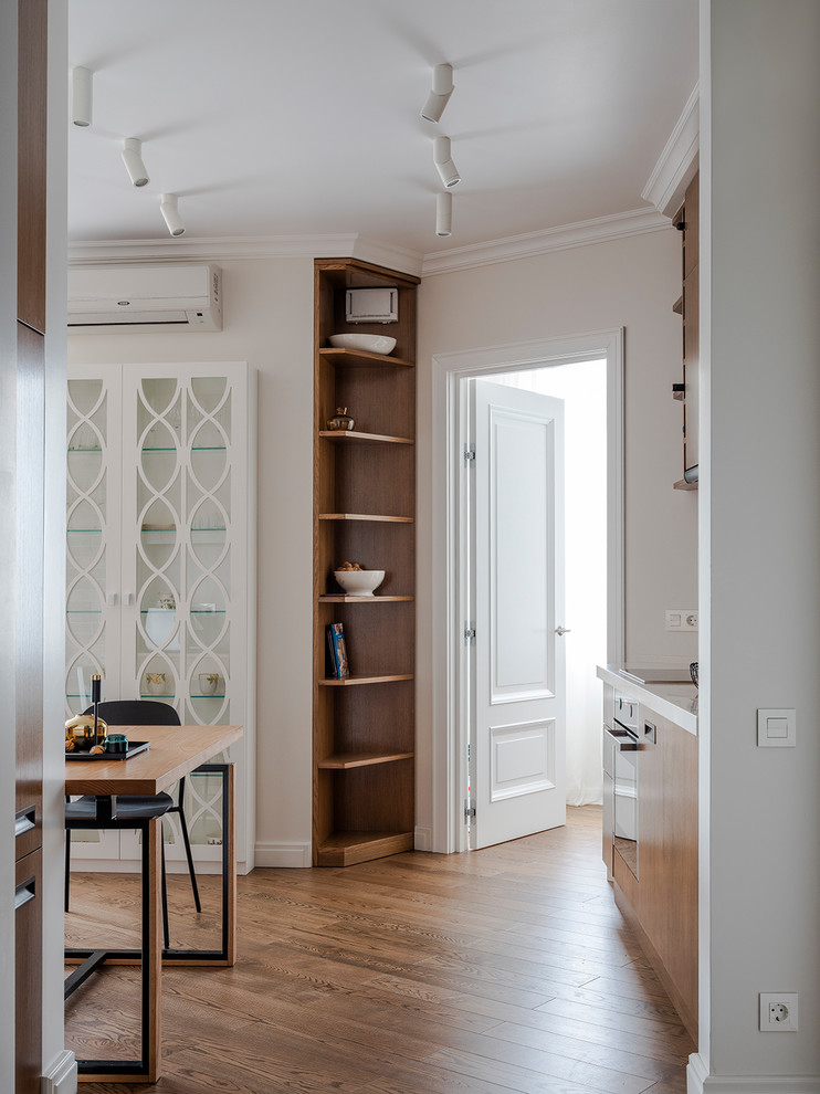 This is an example of a medium sized contemporary single-wall open plan kitchen in Moscow with flat-panel cabinets, medium wood cabinets, composite countertops, medium hardwood flooring, no island, brown floors and white worktops.