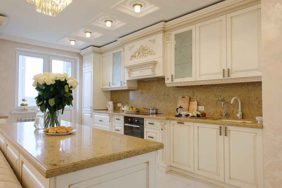 Inspiration for a large traditional galley open plan kitchen in Moscow with raised-panel cabinets, beige cabinets, engineered stone countertops, brown splashback, marble splashback, black appliances, marble flooring, an island, beige floors and brown worktops.