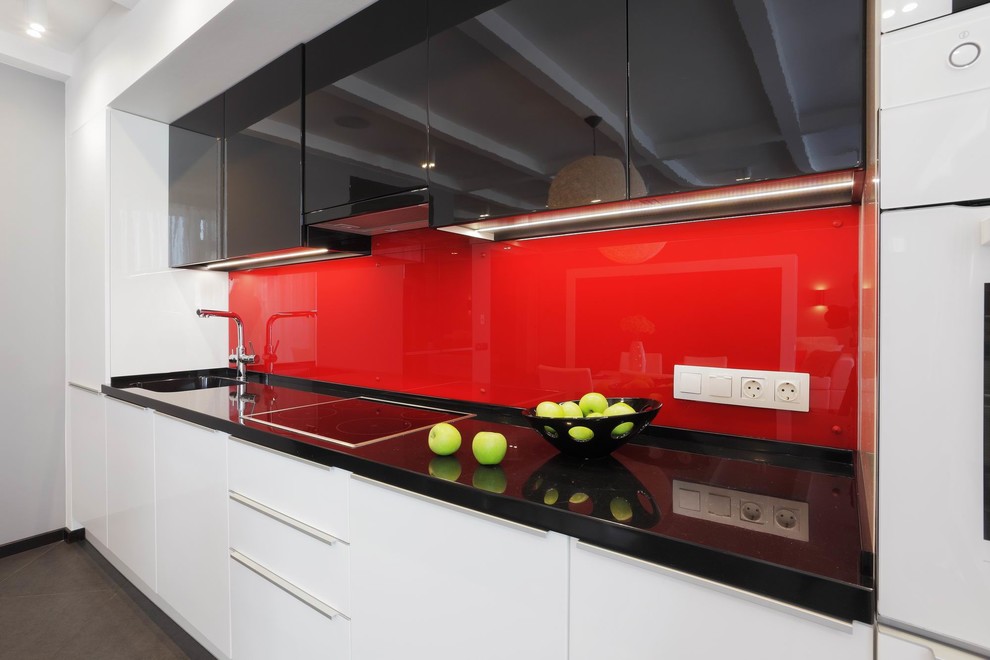 Medium sized contemporary single-wall kitchen/diner in Yekaterinburg with a submerged sink, flat-panel cabinets, black cabinets, red splashback, glass sheet splashback, stainless steel appliances, porcelain flooring and grey floors.