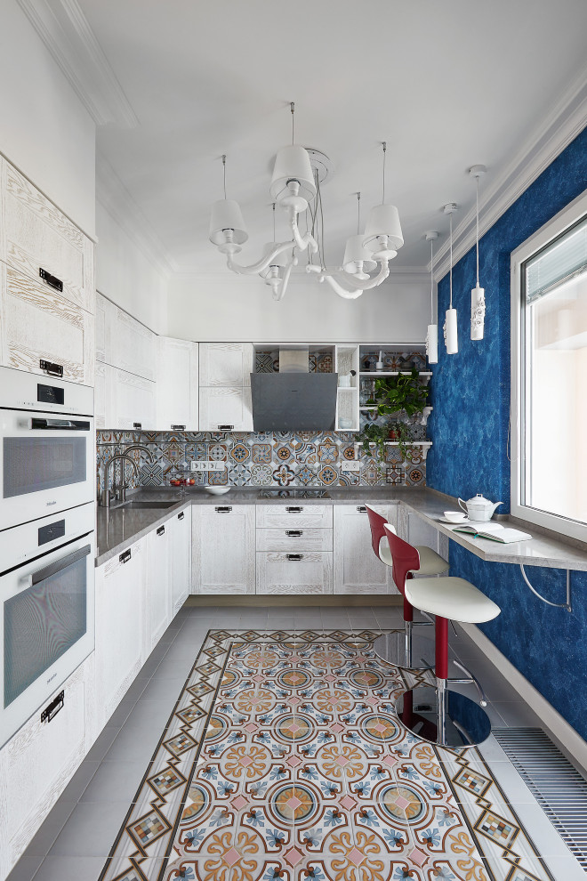 Источник вдохновения для домашнего уюта: п-образная, светлая кухня в современном стиле с врезной мойкой, фасадами в стиле шейкер, белыми фасадами, разноцветным фартуком, фартуком из плитки мозаики, полуостровом, серым полом и серой столешницей