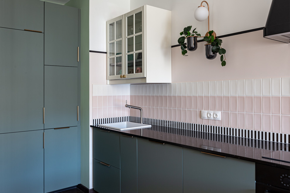 Bild på ett mellanstort nordiskt svart linjärt svart kök och matrum, med en nedsänkt diskho, släta luckor, gröna skåp, granitbänkskiva, rosa stänkskydd, stänkskydd i keramik, svarta vitvaror, klinkergolv i porslin och brunt golv