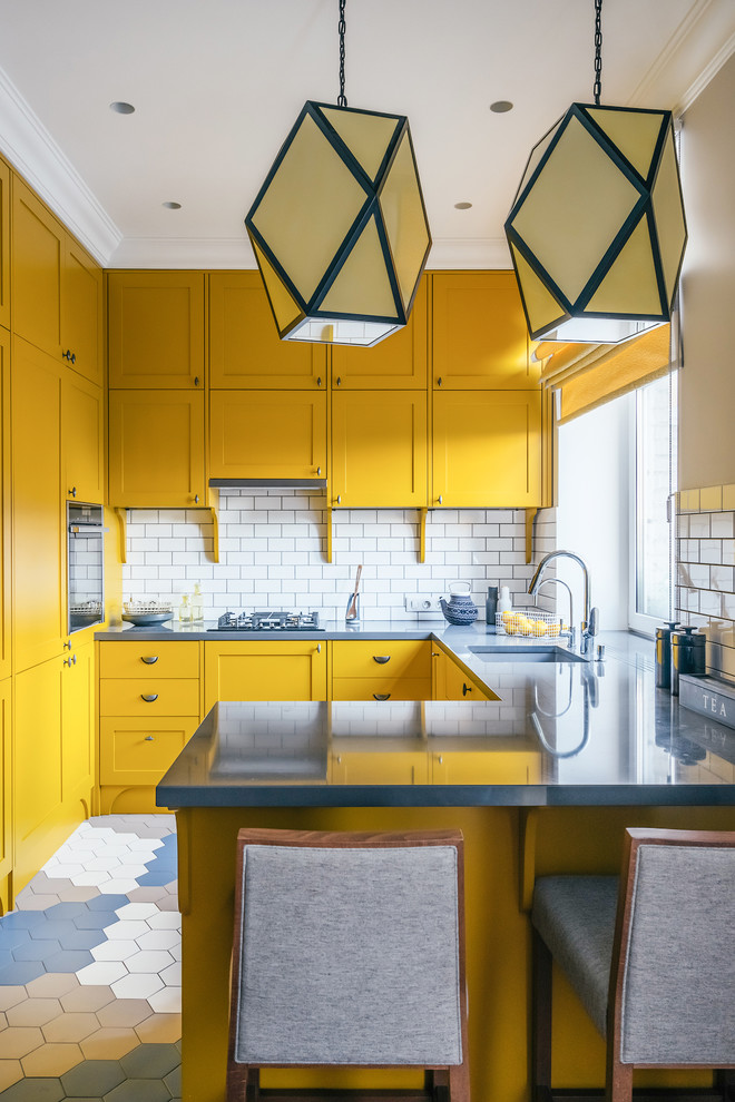 Пример оригинального дизайна: п-образная кухня-гостиная в современном стиле с врезной мойкой, фасадами с утопленной филенкой, желтыми фасадами, белым фартуком, черной техникой, полуостровом и барной стойкой