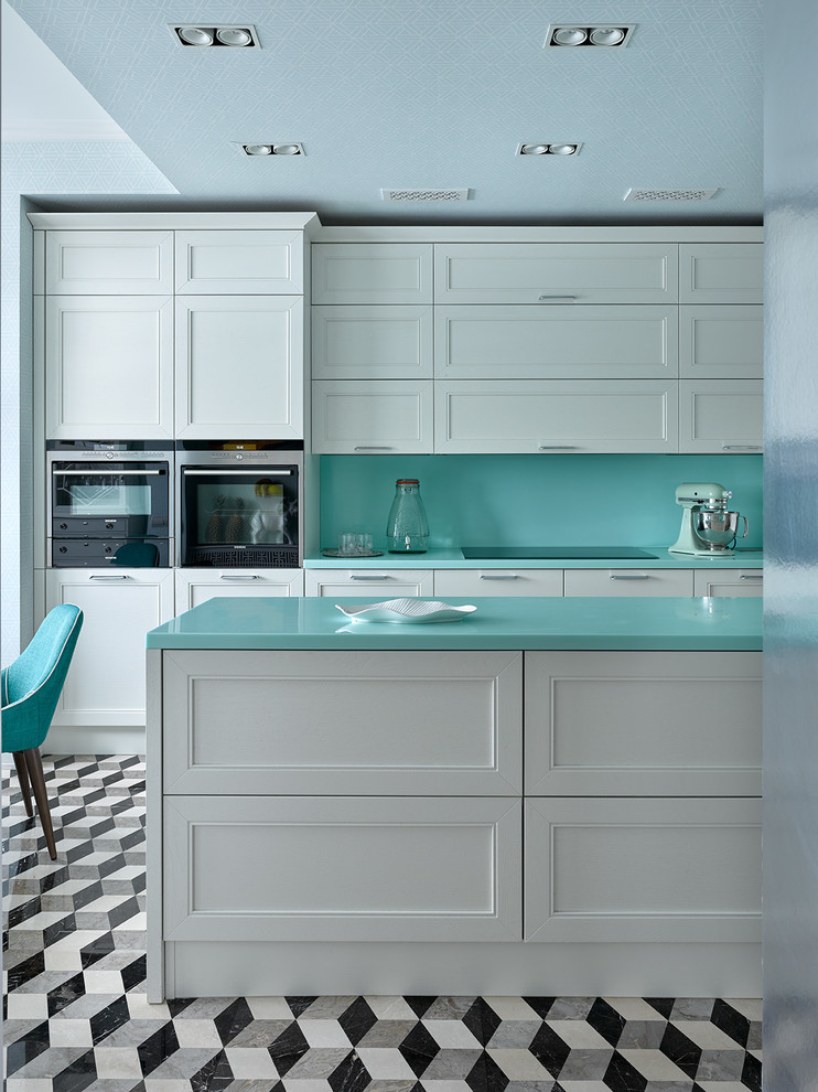 Cette image montre une cuisine bohème avec un placard avec porte à panneau encastré, des portes de placard blanches, îlot, un sol multicolore et une crédence bleue.