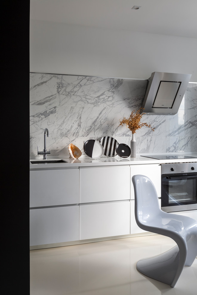 Immagine di una cucina contemporanea chiusa con lavello sottopiano, ante lisce, ante bianche, paraspruzzi grigio, elettrodomestici in acciaio inossidabile, pavimento bianco e top bianco