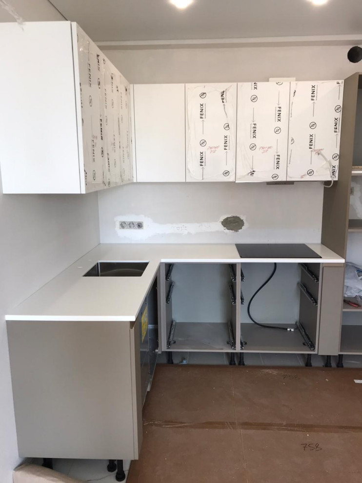 Photo of a small contemporary l-shaped enclosed kitchen in Moscow with a submerged sink, white cabinets, composite countertops, white splashback, no island and white worktops.