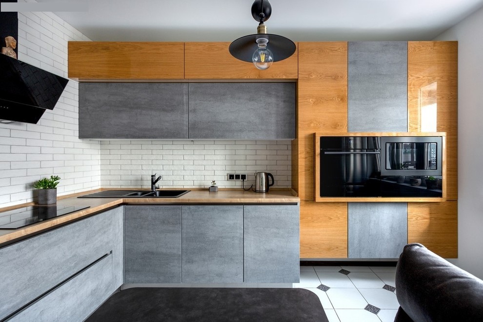 Exempel på ett modernt l-kök, med laminatbänkskiva, vitt stänkskydd, stänkskydd i tegel, svarta vitvaror, klinkergolv i keramik, en dubbel diskho, släta luckor, grå skåp och flerfärgat golv