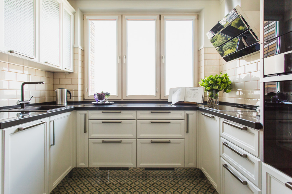 Inredning av ett klassiskt mellanstort kök, med en nedsänkt diskho, luckor med infälld panel, vita skåp, beige stänkskydd och svarta vitvaror