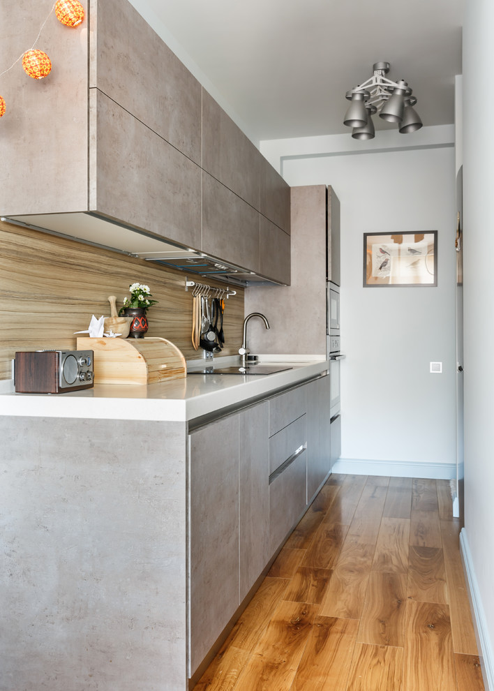 Immagine di una cucina lineare design chiusa con ante lisce, ante grigie, paraspruzzi beige, pavimento in legno massello medio, nessuna isola, pavimento marrone e top bianco