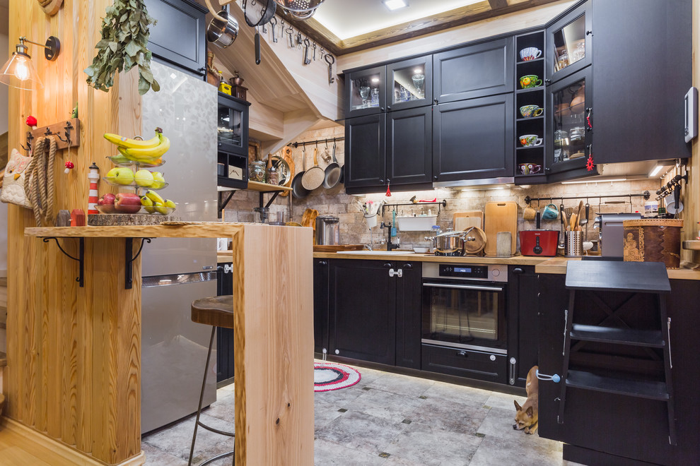 Modern inredning av ett kök, med en nedsänkt diskho, skåp i shakerstil, svarta skåp, träbänkskiva, beige stänkskydd, rostfria vitvaror och en halv köksö
