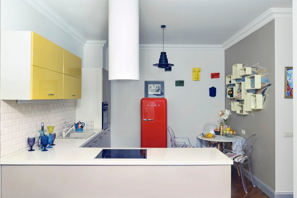 Cette image montre une cuisine ouverte design en L avec un évier posé, un placard à porte plane, une crédence blanche, une crédence en carrelage métro, un électroménager noir et une péninsule.