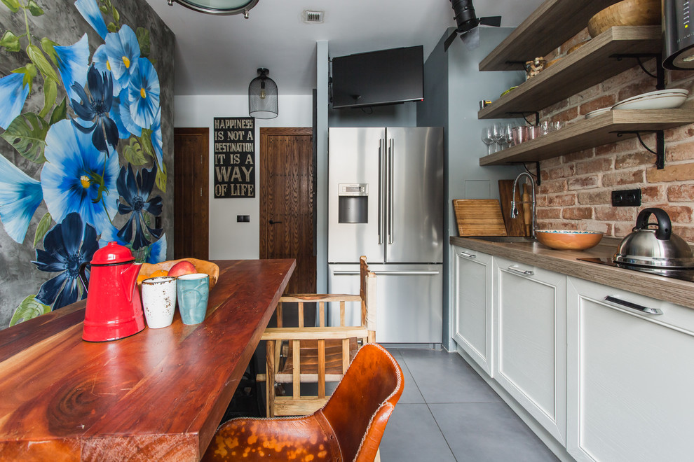 Urban single-wall enclosed kitchen in Moscow with recessed-panel cabinets, white cabinets, brown splashback, brick splashback, stainless steel appliances, no island, grey floors and a single-bowl sink.