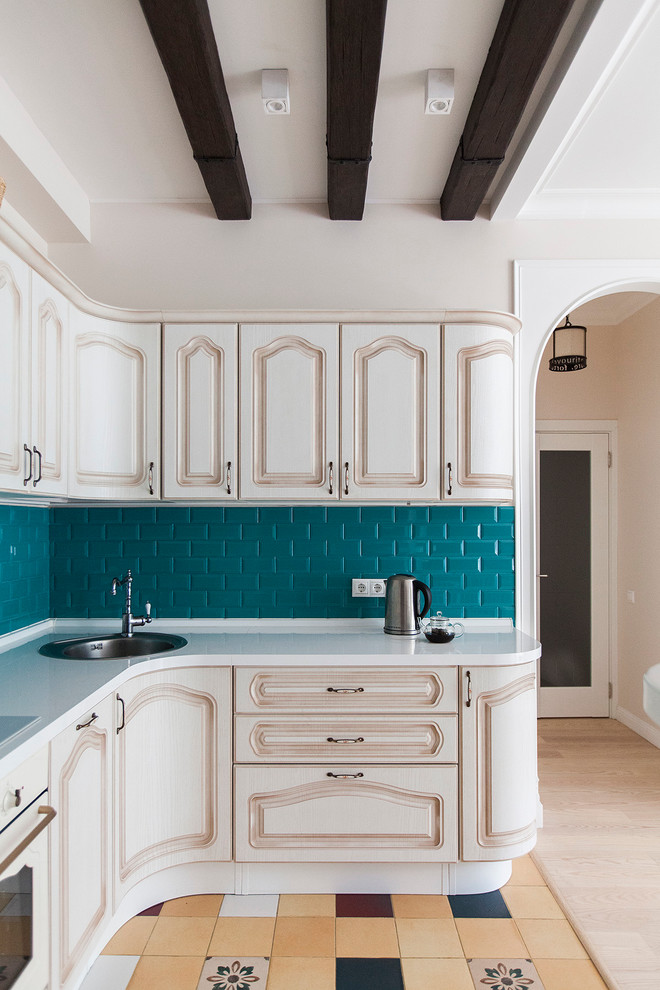 Inspiration for an eclectic open plan kitchen in Moscow with white cabinets, a built-in sink, raised-panel cabinets, blue splashback, metro tiled splashback and white appliances.