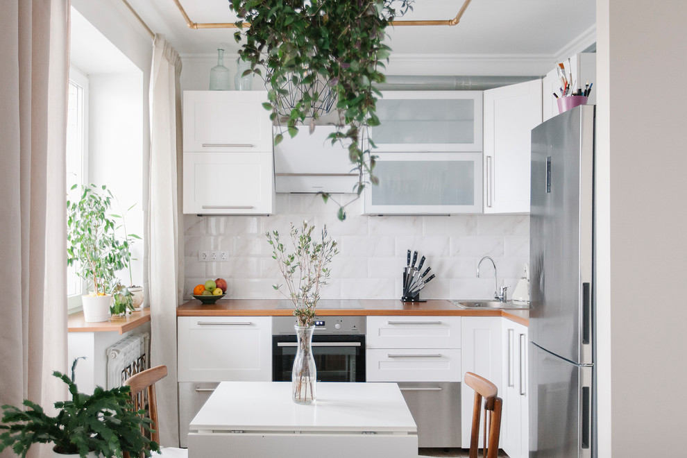 Offene Moderne Küche ohne Insel in L-Form mit Einbauwaschbecken, Schrankfronten mit vertiefter Füllung, weißen Schränken, Küchenrückwand in Weiß und Küchengeräten aus Edelstahl in Moskau