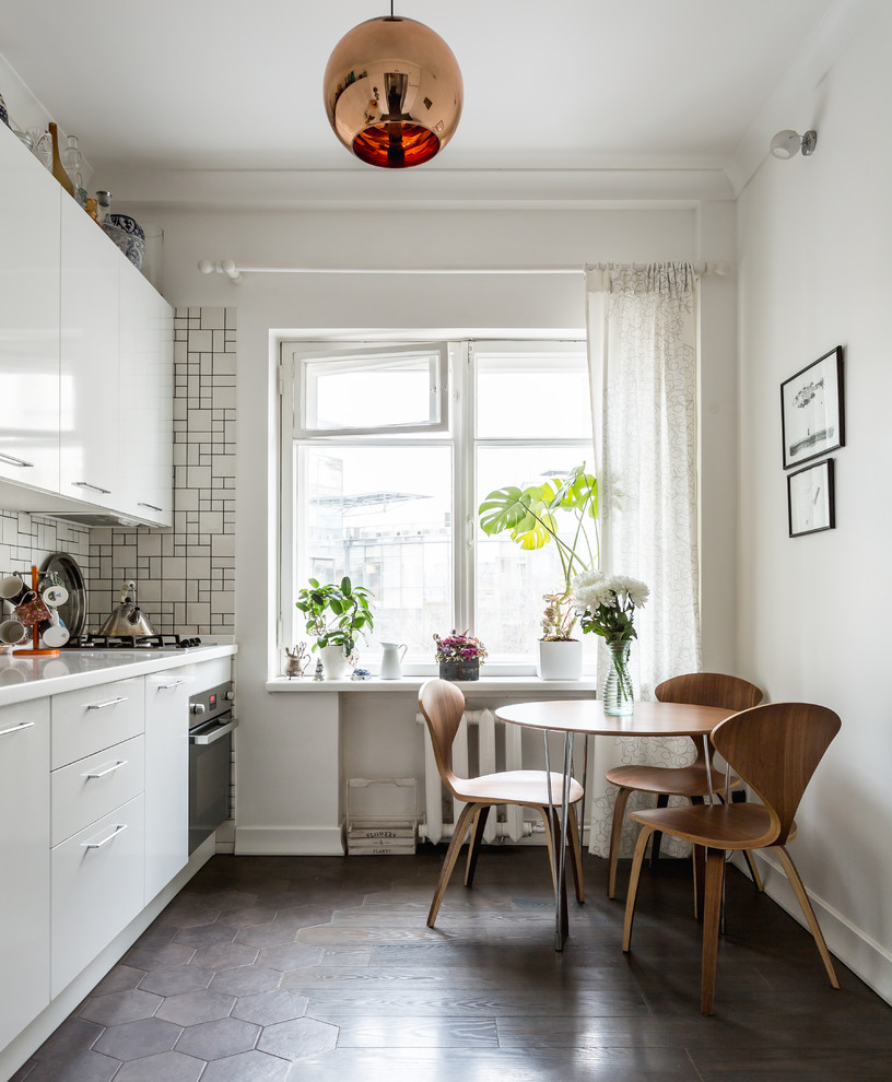 Exempel på ett modernt kök och matrum, med släta luckor, vita skåp, vitt stänkskydd, rostfria vitvaror och brunt golv