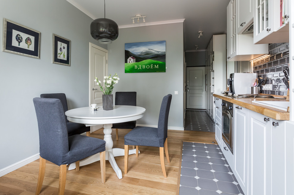 Idée de décoration pour une cuisine américaine design avec un évier posé, un placard avec porte à panneau surélevé, des portes de placard blanches, un plan de travail en bois, une crédence grise, une crédence en carrelage métro, un électroménager en acier inoxydable et aucun îlot.