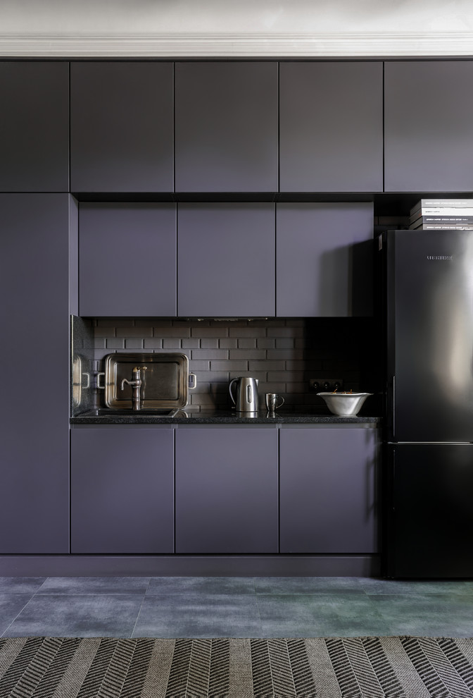 Inredning av ett modernt svart linjärt svart kök med öppen planlösning, med en nedsänkt diskho, släta luckor, grå skåp, granitbänkskiva, grått stänkskydd, stänkskydd i tegel, klinkergolv i porslin och grått golv