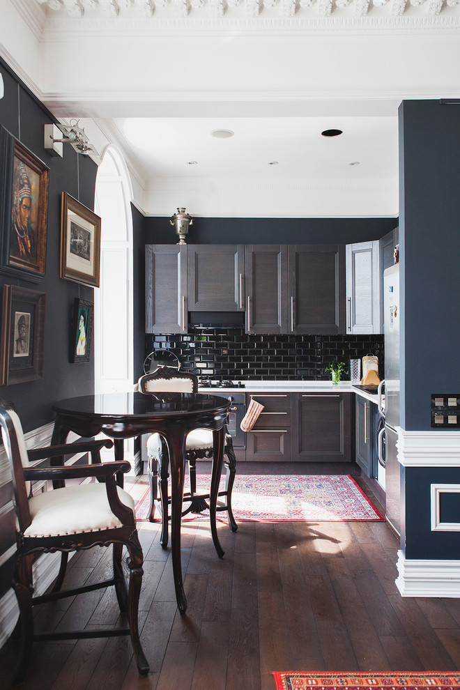 На фото: угловая кухня-гостиная в классическом стиле с фасадами с утопленной филенкой, черными фасадами, черным фартуком и темным паркетным полом без острова с
