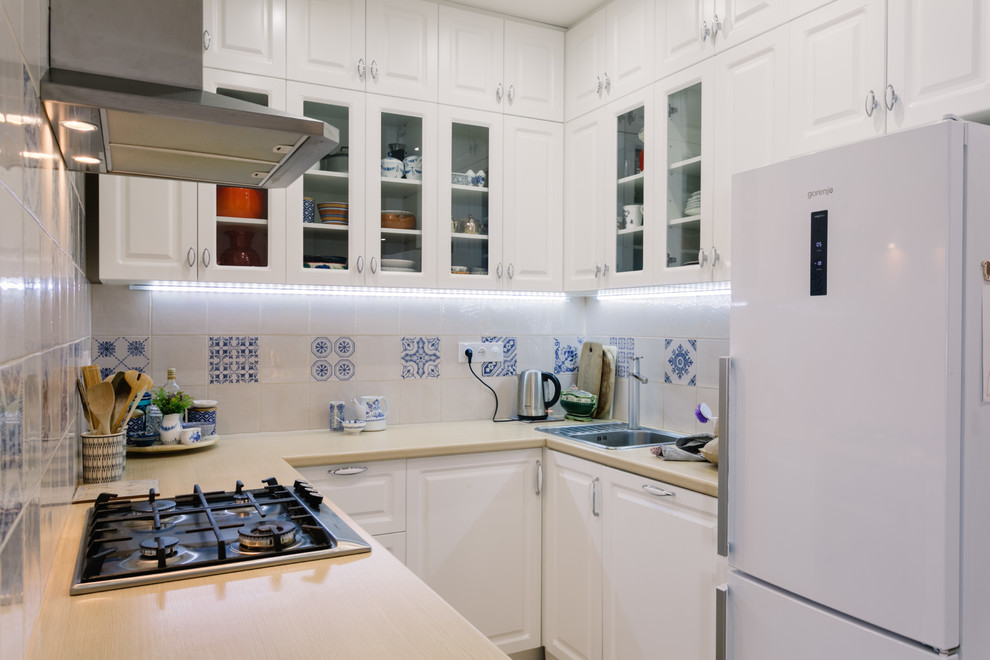Foto på ett nordiskt kök, med en nedsänkt diskho, luckor med upphöjd panel, vita skåp och vitt stänkskydd