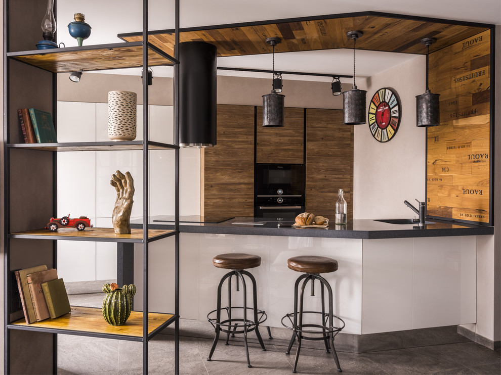 Idee per una cucina ad ambiente unico minimal con elettrodomestici neri, penisola e pavimento grigio
