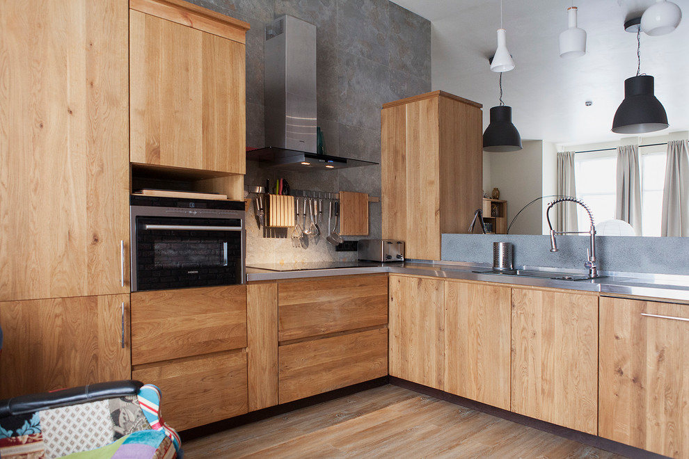 Foto di una cucina design con ante lisce, ante in legno scuro, paraspruzzi grigio, pavimento in legno massello medio, elettrodomestici in acciaio inossidabile e lavello da incasso
