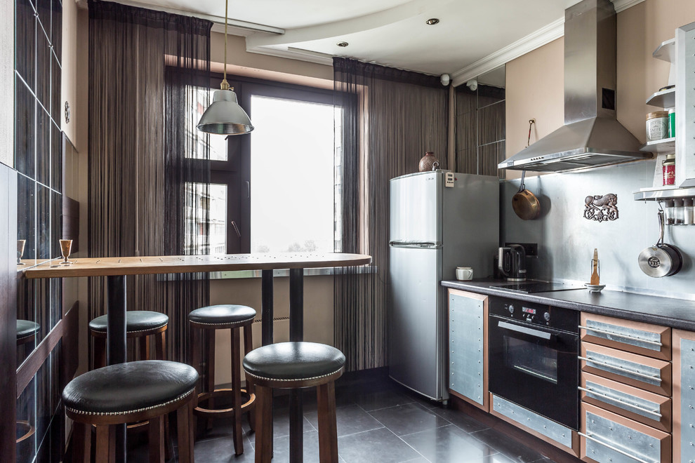 Inspiration för ett avskilt funkis linjärt kök, med släta luckor, skåp i rostfritt stål, stänkskydd med metallisk yta och svart golv