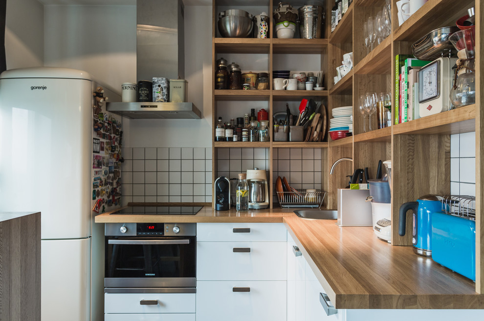 Foto di una cucina design con lavello da incasso, ante lisce, ante bianche, top in legno, paraspruzzi bianco e elettrodomestici in acciaio inossidabile