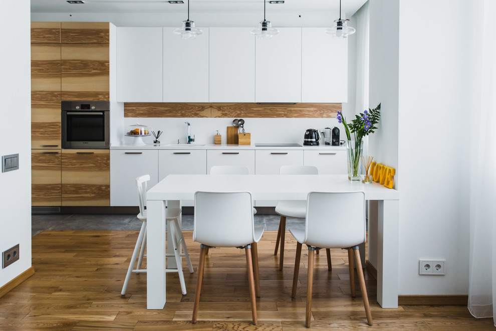 Foto de cocina lineal escandinava abierta sin isla con armarios con paneles lisos, salpicadero blanco, electrodomésticos de acero inoxidable y suelo de madera en tonos medios
