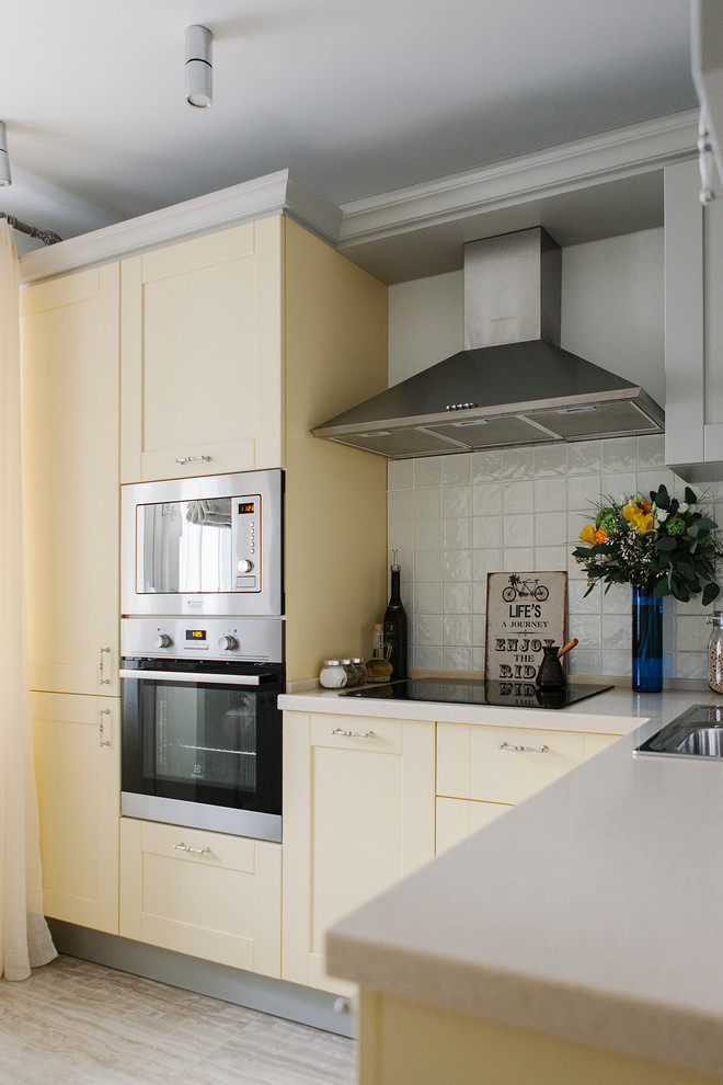モスクワにある小さなトラディショナルスタイルのおしゃれなキッチン (ドロップインシンク、シェーカースタイル扉のキャビネット、黄色いキャビネット、白いキッチンパネル、シルバーの調理設備、アイランドなし、ベージュの床) の写真