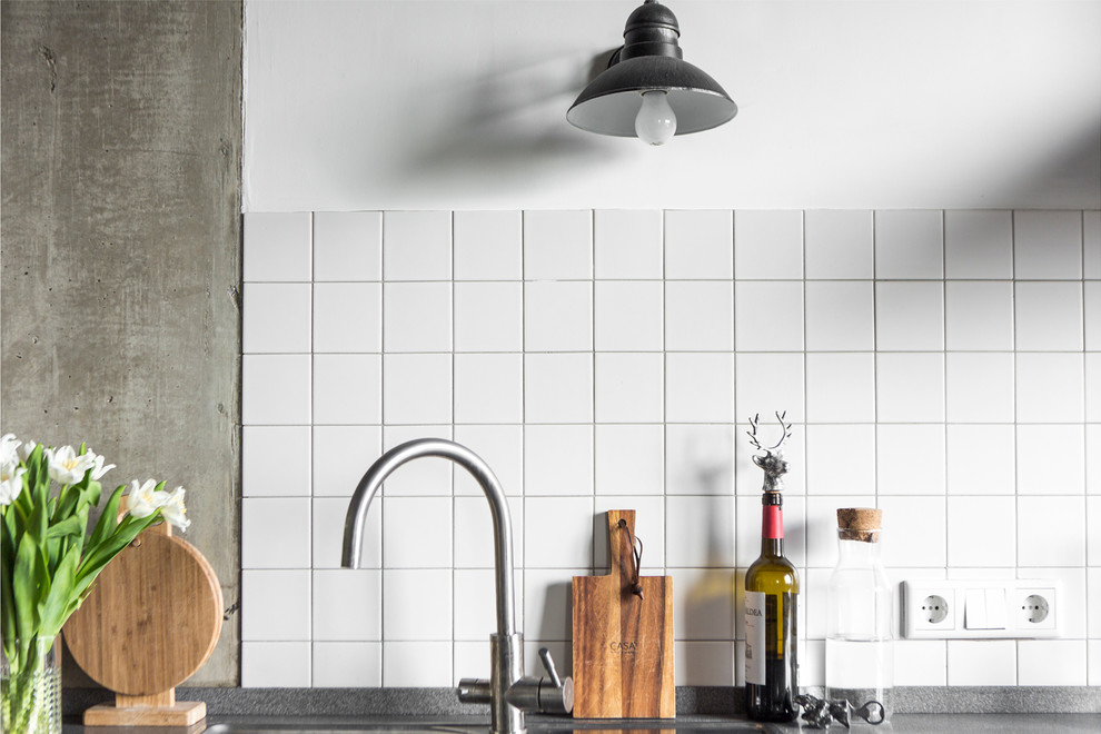 Foto på ett industriellt kök, med en nedsänkt diskho, släta luckor, vitt stänkskydd, rostfria vitvaror och en köksö