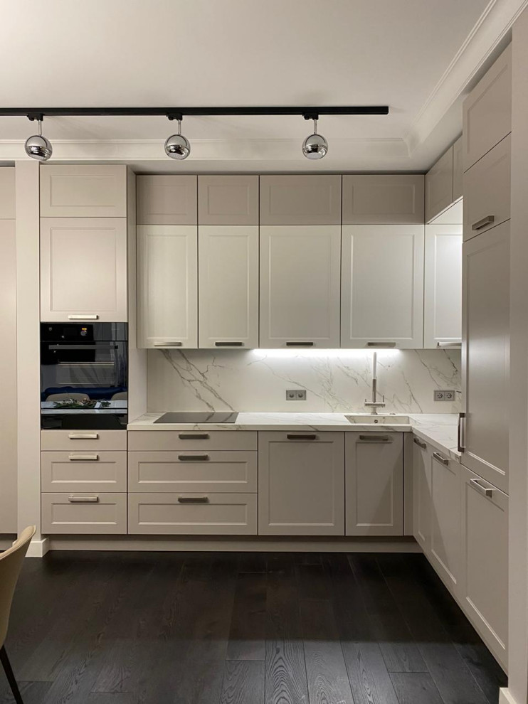 Large classic l-shaped open plan kitchen in Other with recessed-panel cabinets, white cabinets, white splashback, brown floors and white worktops.