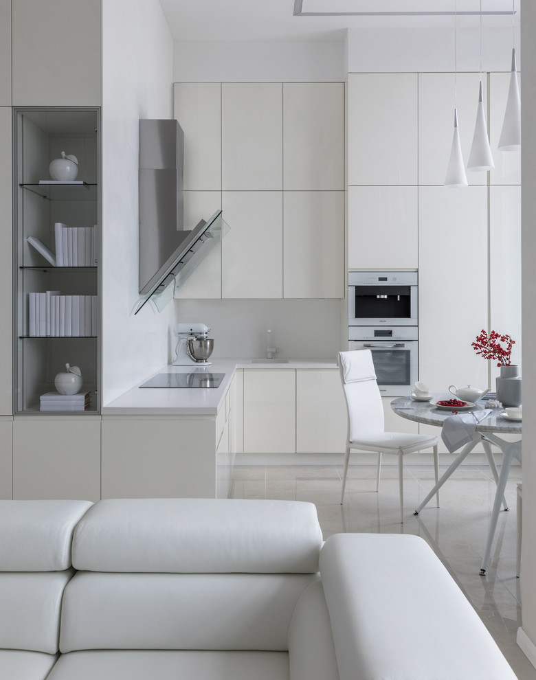 Modern inredning av ett litet vit vitt kök, med släta luckor, vita skåp, vitt stänkskydd, vita vitvaror, klinkergolv i porslin, beiget golv och en undermonterad diskho