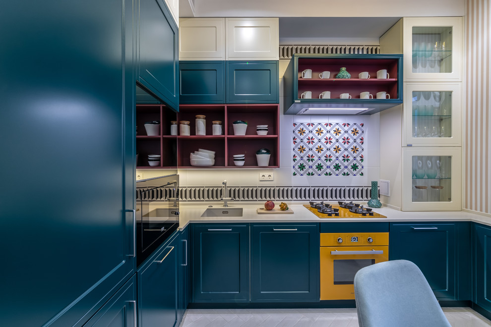 Inredning av ett avskilt, litet beige beige u-kök, med en integrerad diskho, luckor med upphöjd panel, blå skåp, bänkskiva i koppar, flerfärgad stänkskydd, stänkskydd i keramik och färgglada vitvaror