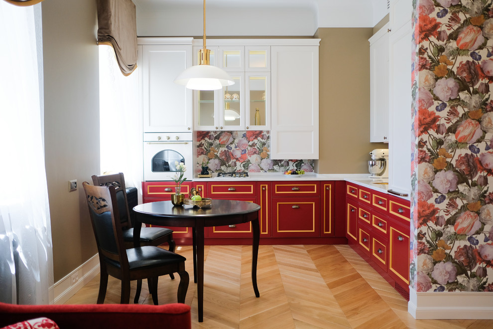 This is an example of a small traditional l-shaped kitchen/diner in Moscow with red cabinets, composite countertops, multi-coloured splashback, white appliances, medium hardwood flooring, no island, white worktops, a submerged sink, brown floors and recessed-panel cabinets.
