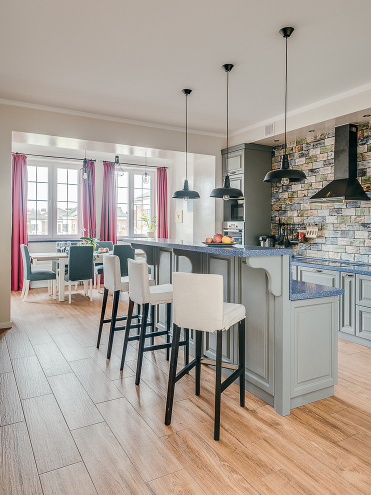 Foto på ett stort vintage blå kök och matrum, med luckor med upphöjd panel, blå skåp, flerfärgad stänkskydd, en köksö, brunt golv, en rustik diskho, stänkskydd i keramik, integrerade vitvaror och klinkergolv i porslin