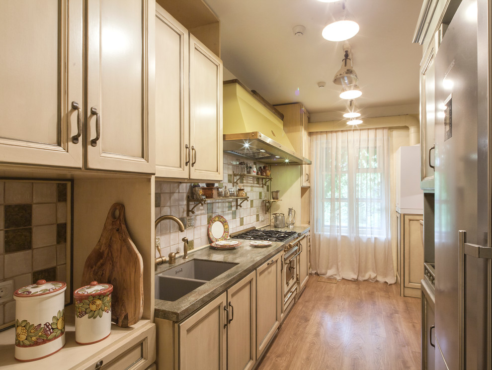 Idée de décoration pour une cuisine linéaire champêtre avec un évier 2 bacs, un placard avec porte à panneau encastré, des portes de placard beiges, une crédence beige, un électroménager blanc et un sol en bois brun.