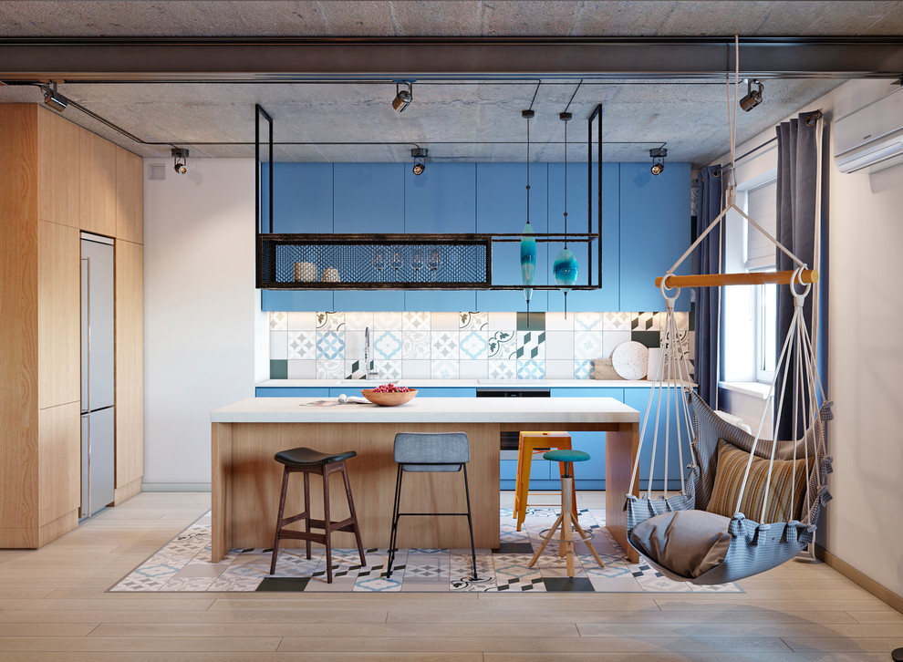 Industrial l-shaped kitchen/diner in Other with flat-panel cabinets, blue cabinets, multi-coloured splashback, stainless steel appliances, light hardwood flooring, an island, brown floors and white worktops.
