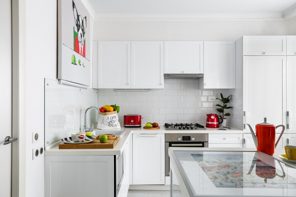 Idéer för ett modernt vit l-kök, med en nedsänkt diskho, vita skåp, vitt stänkskydd, stänkskydd i tunnelbanekakel, integrerade vitvaror, en köksö, grått golv och luckor med infälld panel