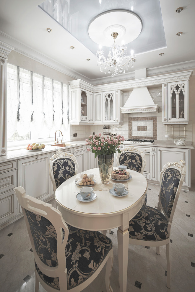 Klassisk inredning av ett mellanstort beige beige kök, med en undermonterad diskho, luckor med profilerade fronter, vita skåp, bänkskiva i kvarts, beige stänkskydd, stänkskydd i mosaik, vita vitvaror, marmorgolv och beiget golv